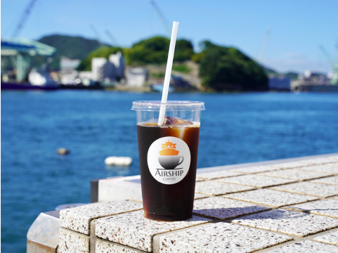 海をバックに地面に置いたコーヒーの写真